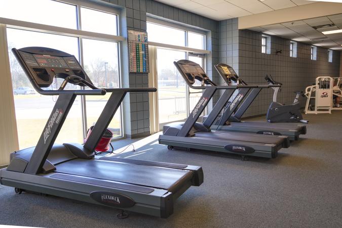 A row of treadmills beside floor-to-ceiling windows in the fitness room.